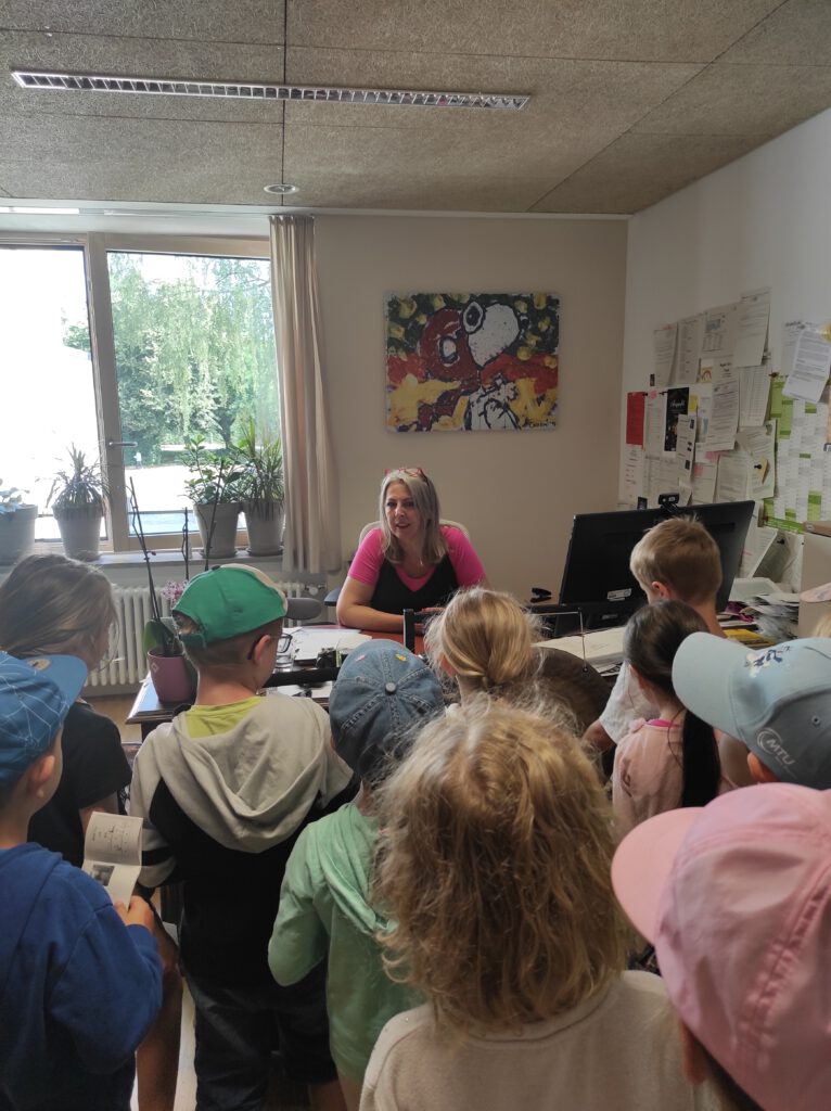 Kindergruppe besucht Frau im Bürogespräch.