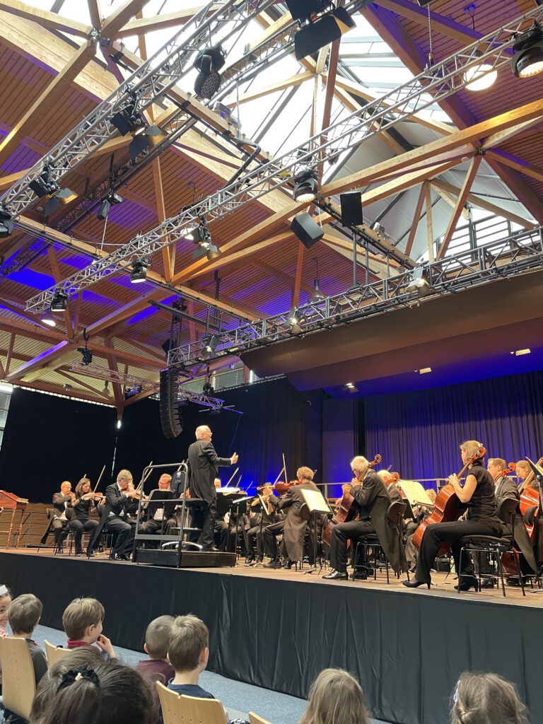 Orchester spielt Konzert unter moderner Holzdecke
