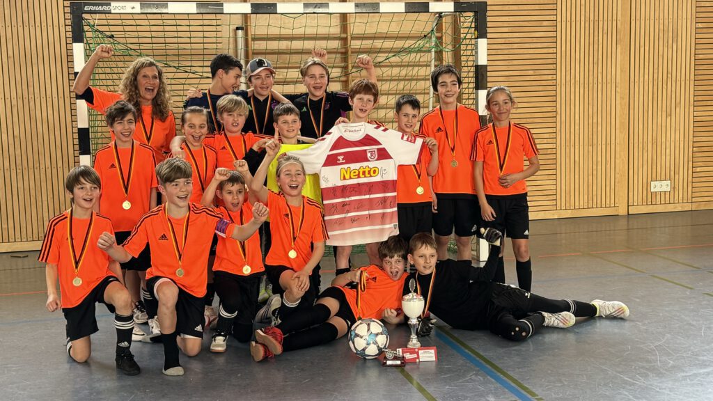 Jugendfußballteam feiert Sieg mit Pokalen und Medaillen
