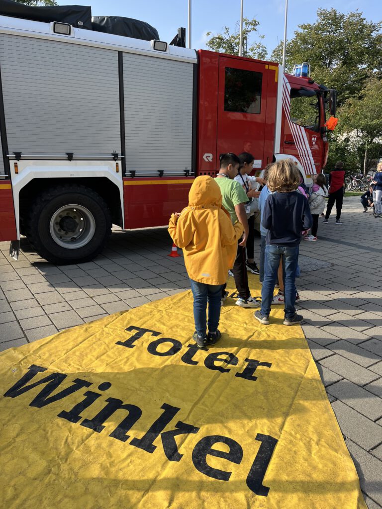 Kinder erkunden Feuerwehrfahrzeug und toten Winkel