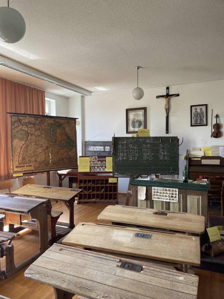 Blick in ein Klassenzimmer von früher, es ist altes Schulmobiliar zu sehen