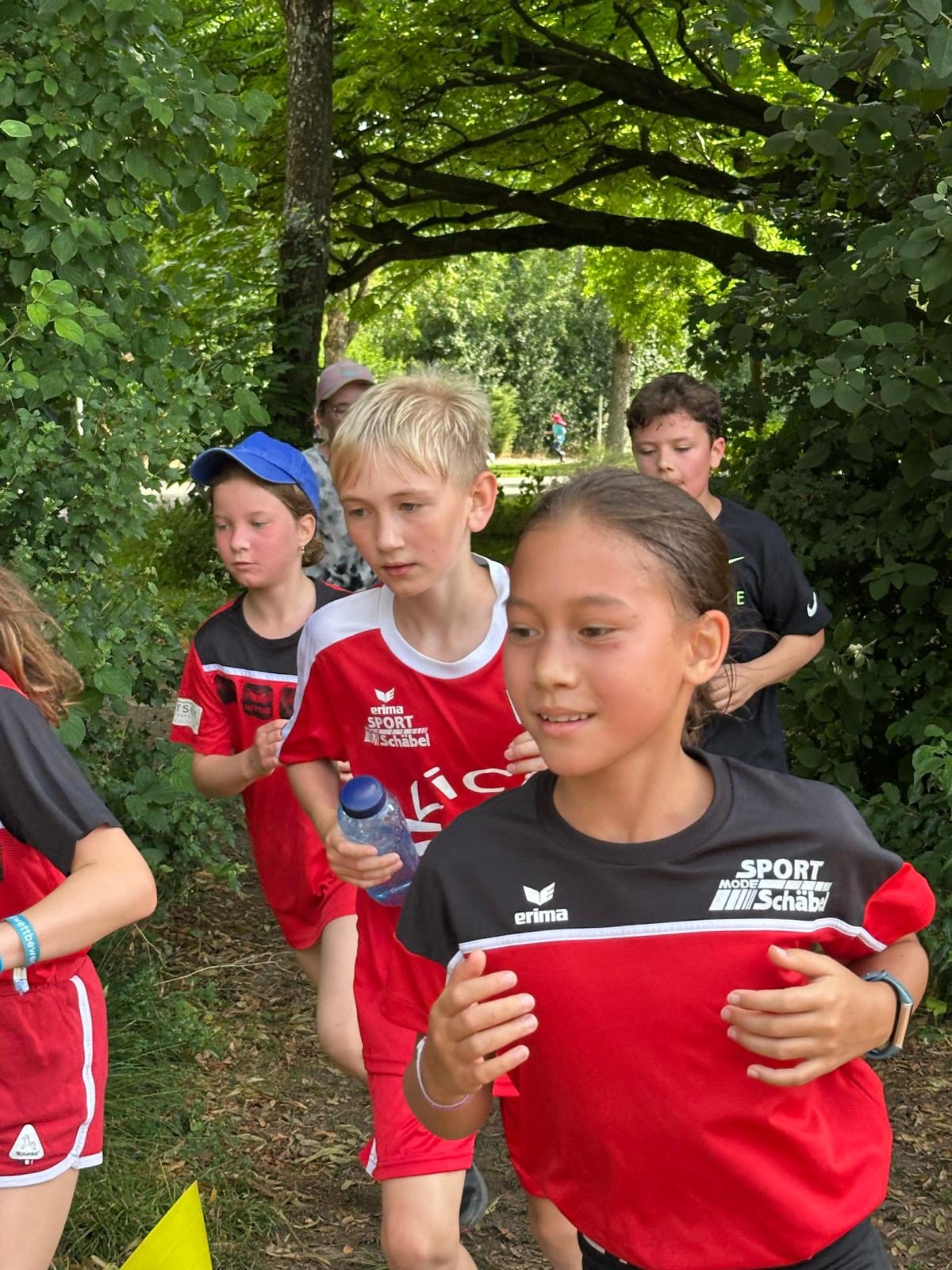 Eine Gruppe von Kindern läuft durch einen kleinen Durchgang zwischen den Bäumen