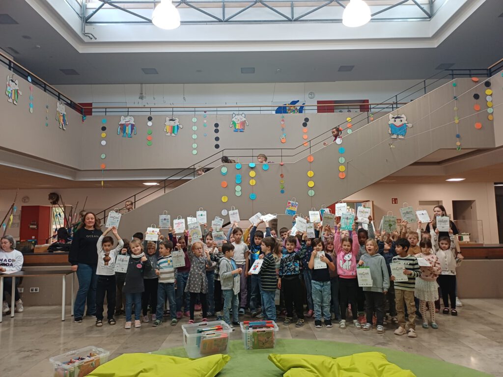 Erstklässler der Grundschule Carl-Orff stehen in der Aula und halten stolz die Lesetüten hoch
