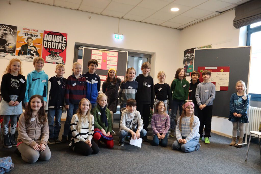 Die am Schulforum teilnehmenden Schüler stehen und knien im Halbkreis.