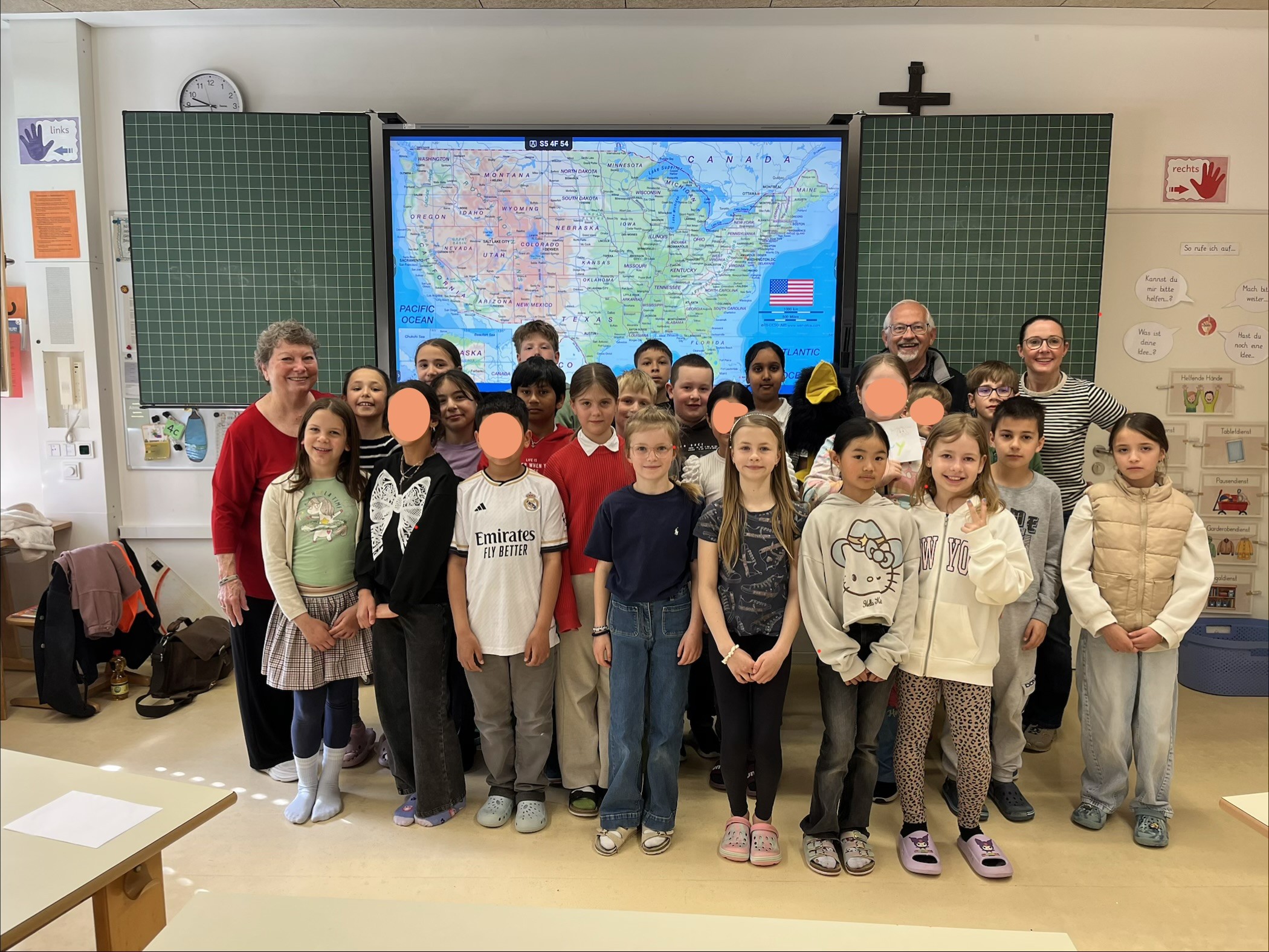 Kinder der Klasse stehen mit dem Besuch aus USA und ihrer Lehrerin vor der interktiven Karte der USA