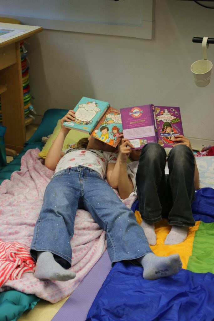 Kinder liegen auf Matratzen und lesen in ihren Büchern